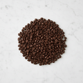 Compact dark roast coffee beans on marble